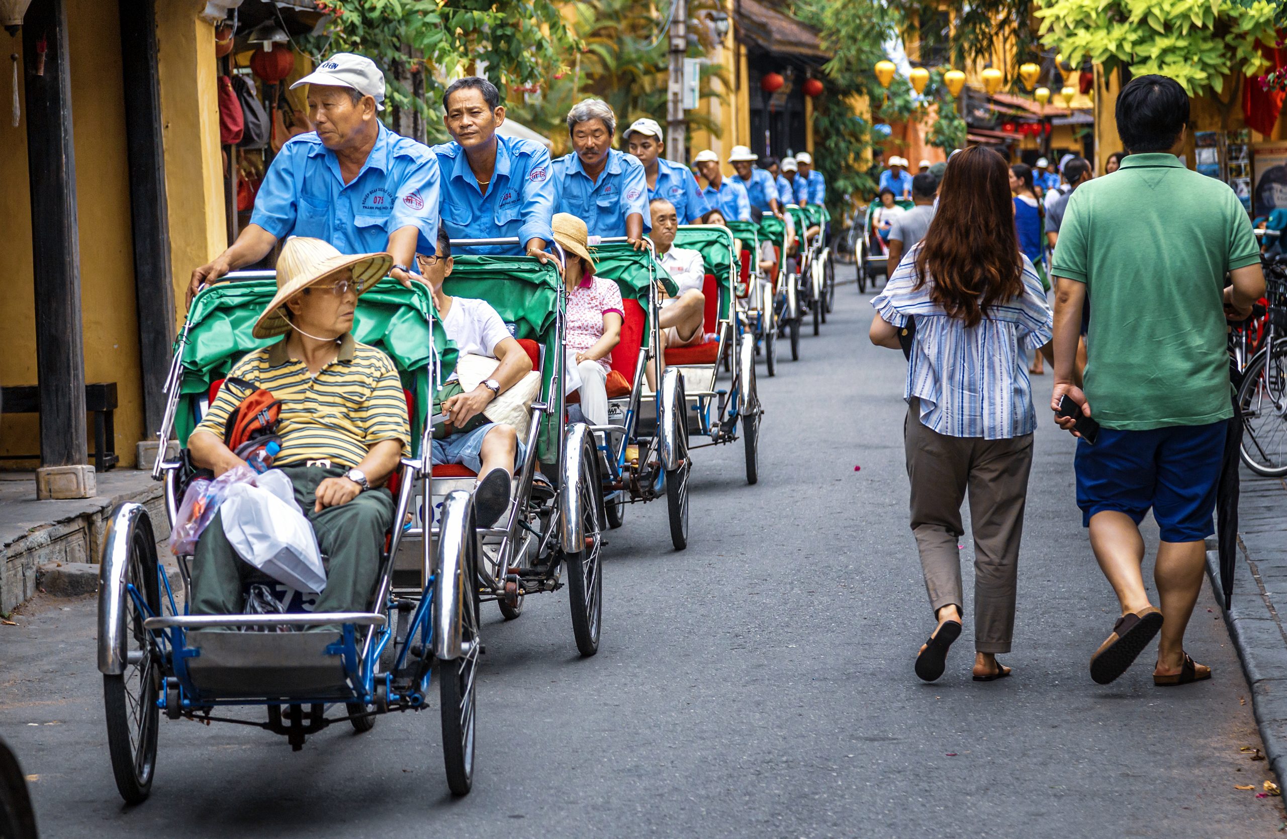 Group of Asian tourists in rickshaws touring Hoi-an Old Town, Vietnam